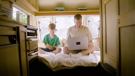 father and son playing chess sitting on the campervan bed