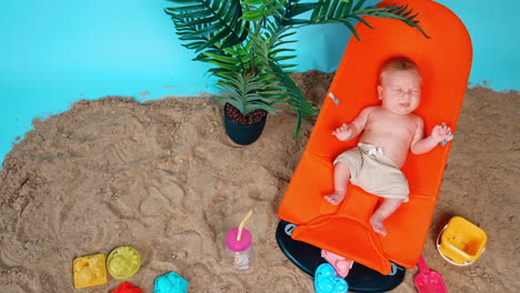 tiny kid lying in the baby chair is unhappy. little infant in shorts starts to cry bitterly. top view.