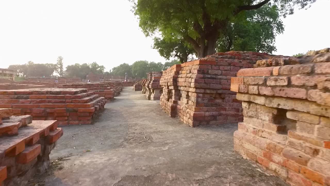 Le antiche rovine del sito archeologico a Sarnath, Varanasi, India, con un primo piano di piedistalli in mattoni.