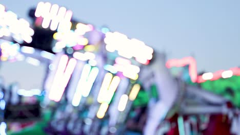 close-up of colorful neon lights on a spinning amusement ride at dusk.