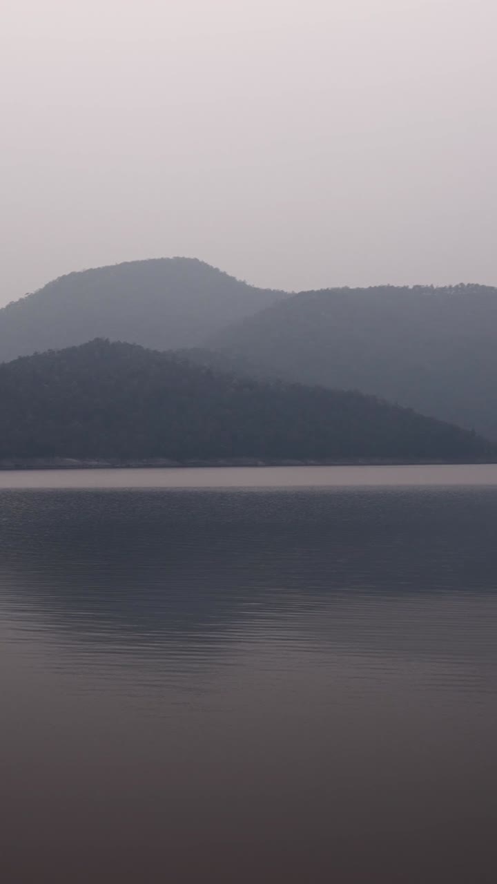 A serene lake landscape with mountains in the fog