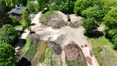 sediment stockpile surrounded by bright green trees with still water mud pools