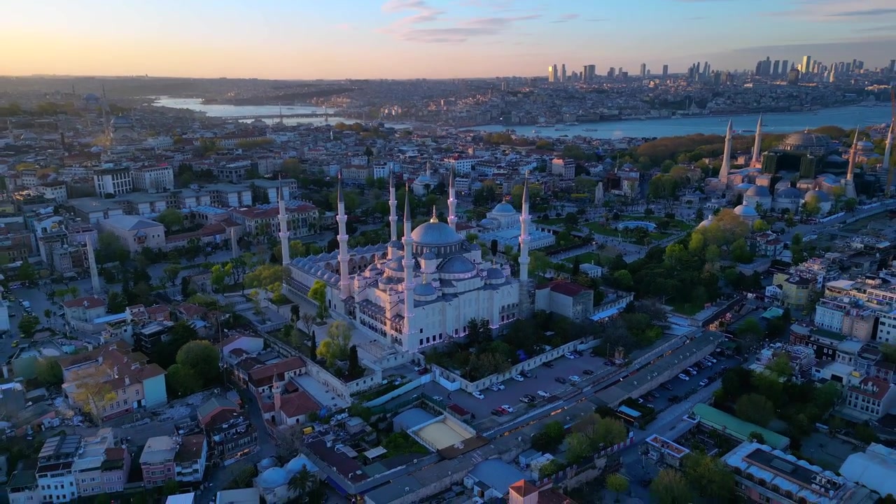 Tarihi mimariyi modern Boğaz silüetiyle harmanlayan ikonik Sultan Ahmed Camii ve Ayasofya ile İstanbul şehir manzarası. Hız rampası, hızlandırılmış ters uçuş panorama drone çekimi.