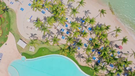 Piscina-En-El-Hotel-De-Playa-Con-Palmeras-En-Un-Día-Soleado-De-Verano-En-Juan-Dolio,-República-Dominicana