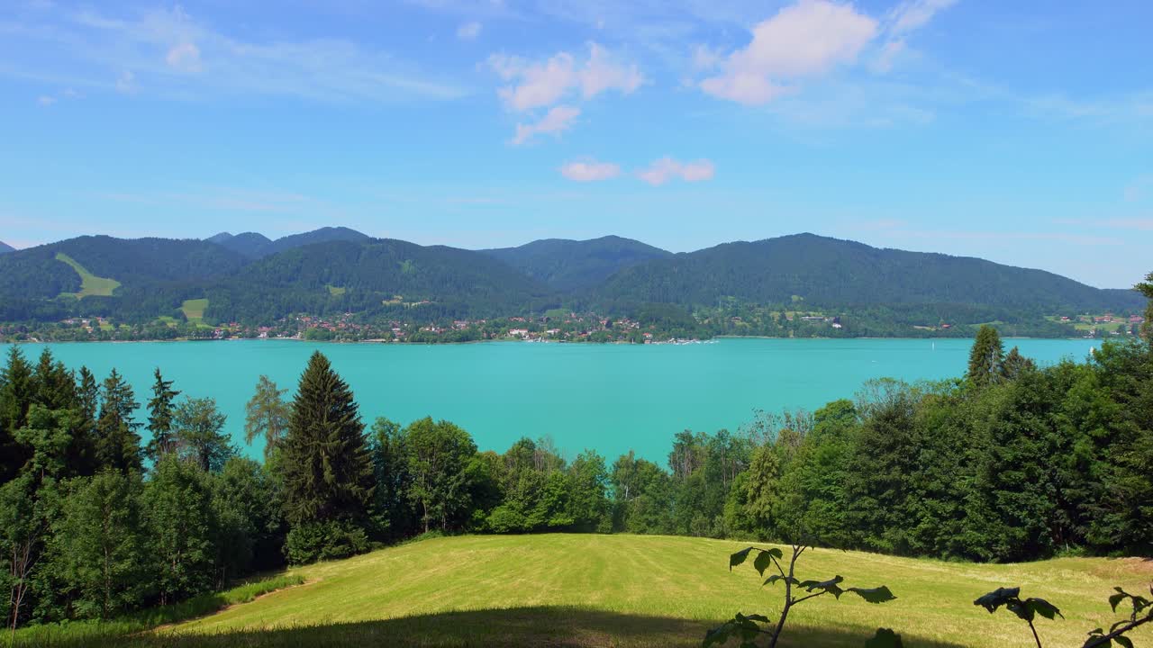 timelapse de viaje: el tegernsee de color turquesa enmarcado por árboles verdes de verano bajo nubes en movimiento en un impresionante día de verano en el sur de baviera, alemania