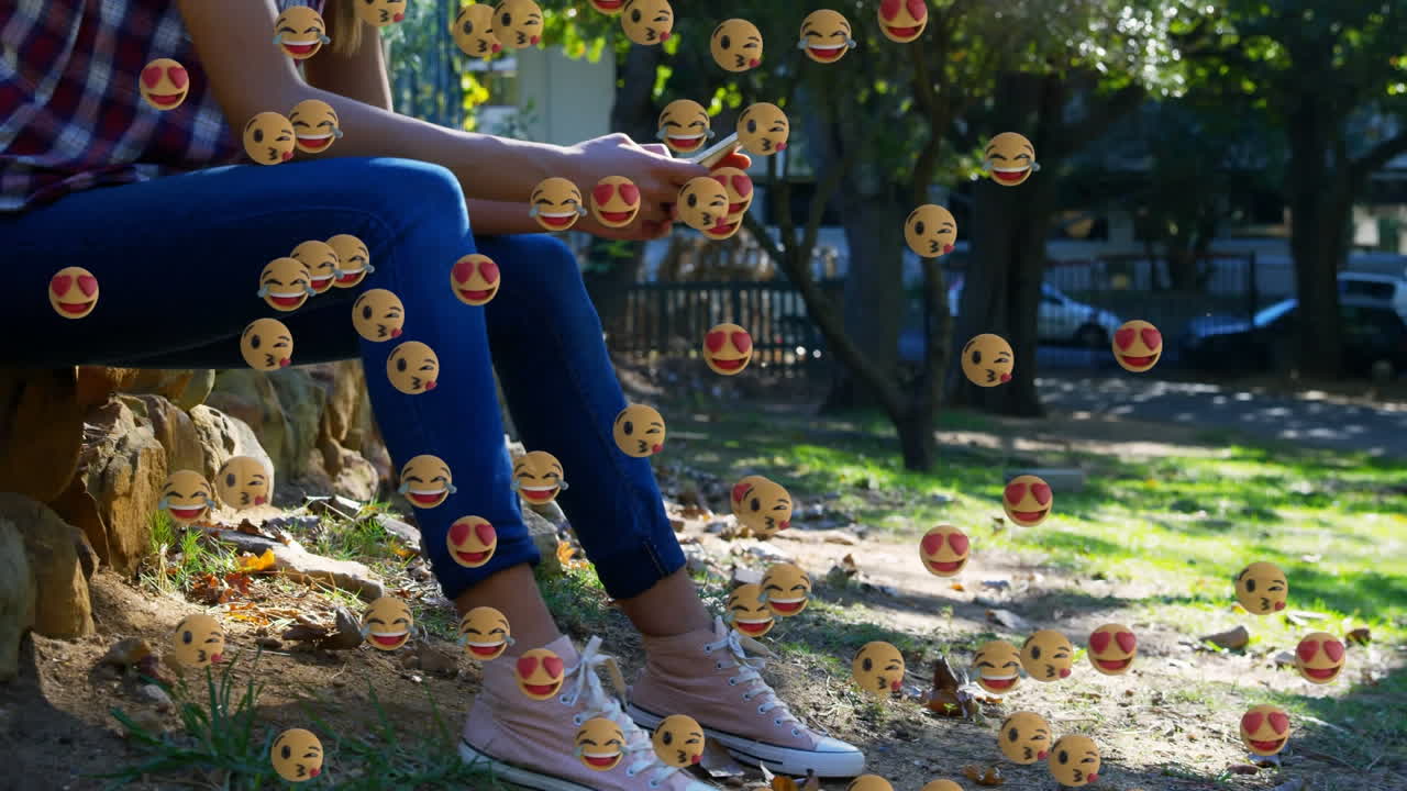 스마트폰을 사용하는 여성 위에 떨어지는 이모티콘의 애니메이션