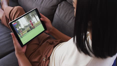 composite of woman sitting at home on couch watching hockey match on tablet