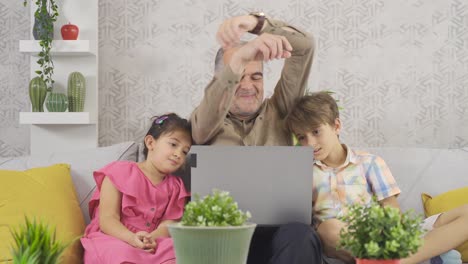 Opa-Schaut-Mit-Seinen-Enkelkindern-Auf-Den-Laptop-Bildschirm.