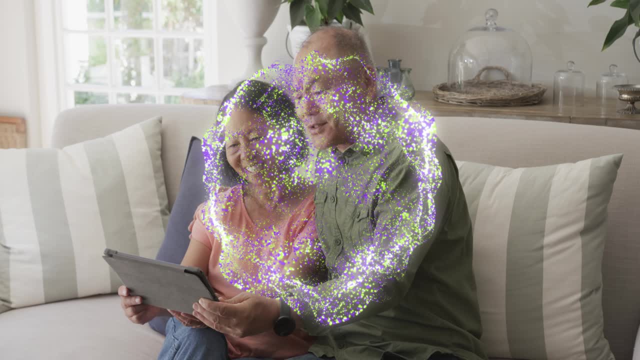 Woman holding tablet, man coming and leaning to share screen, particle ring over hands showing tech