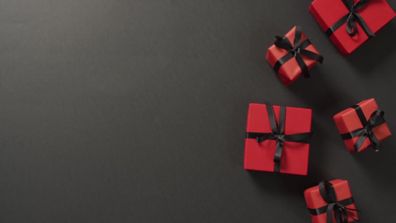 cajas de regalos rojas con cintas negras sobre fondo negro con espacio para copiar