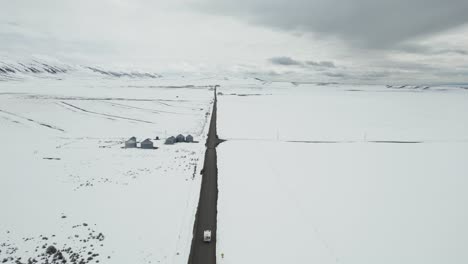 Vista-Aérea-De-Una-Autocaravana-Blanca-Que-Atraviesa-Un-Paisaje-Invernal-Y-Desolado-En-Idaho,-EE.UU.