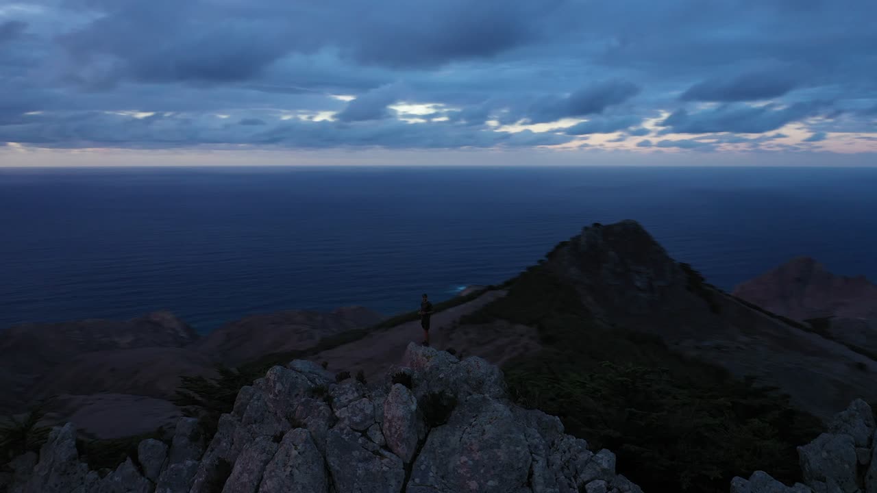 una sola persona parada sola después del atardecer en la cima de una montaña en la oscuridad en porto santo, madeira