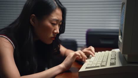 a woman types intently on an old computer keyboard in a low-light environment. the atmosphere shows deep concentration as she works on her task, surrounded by soft shadows.