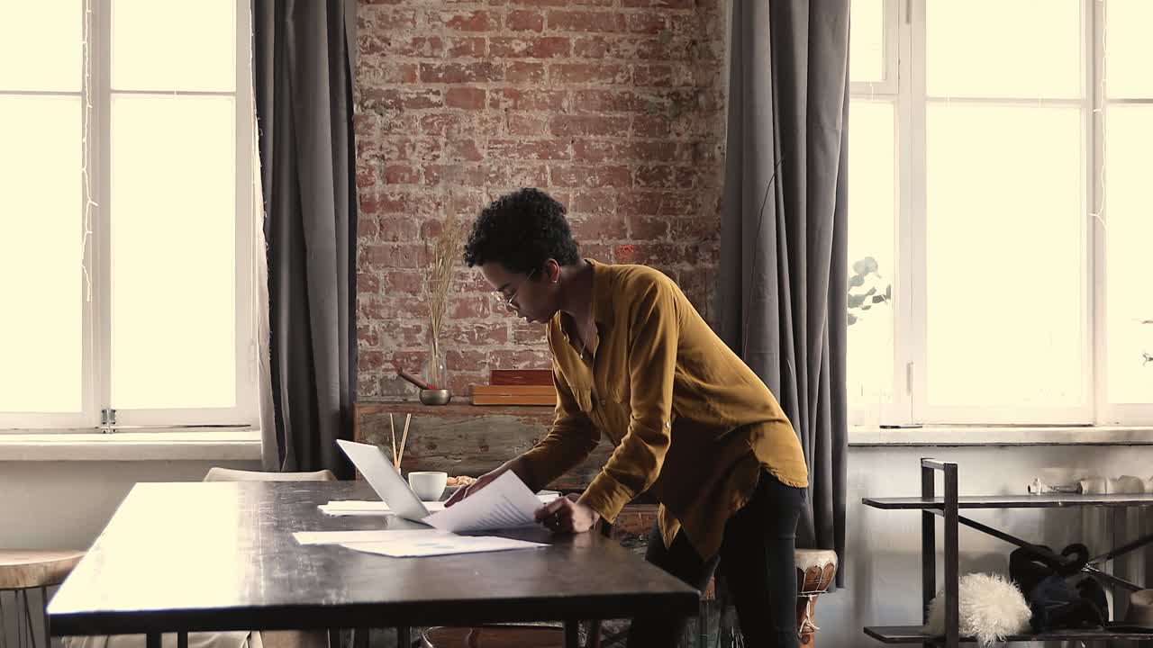 Serious African businesswoman do paperwork, analyze papers, review sales results