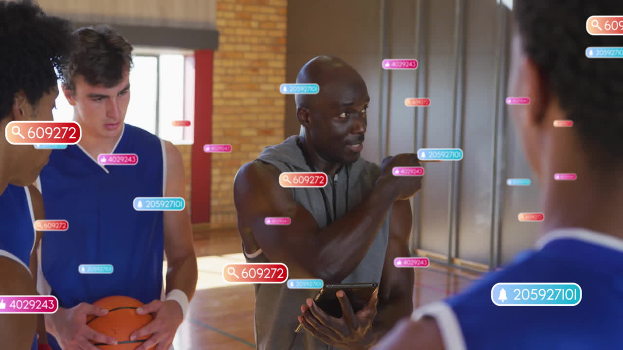 Male coach holding tablet and gesturing on basketball court, showing AR sports analytics data icons