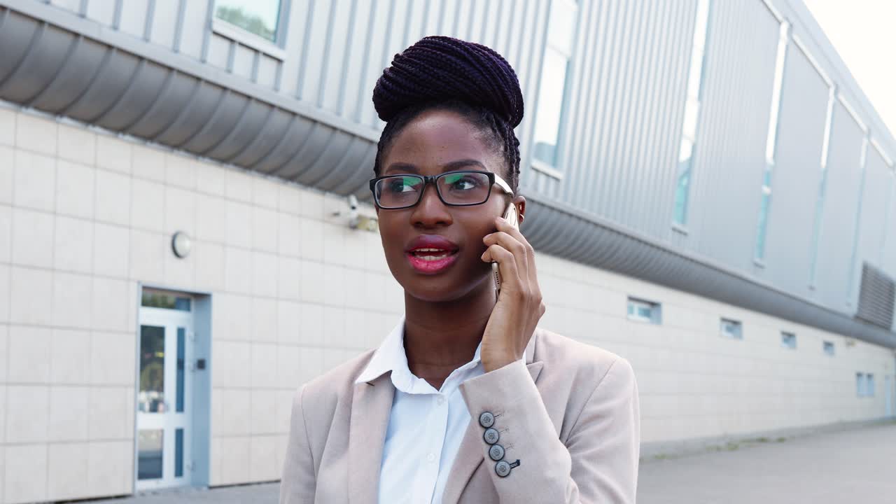 vista de cerca de una mujer de negocios afroamericana con ropa elegante y gafas hablando por teléfono inteligente en la calle