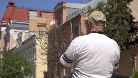 senior man in cap and sunglasses walk in the city and photograph it