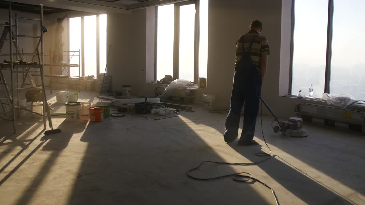 trabajador de la construcción pulindo el suelo en un edificio de oficinas de gran altura en construcción