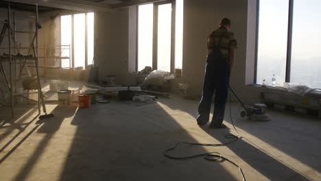 construction worker polishing floor in a high-rise office building under construction