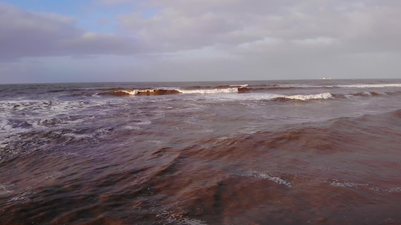 Flying Over Foamy Waves Rolling Onto Shore At Katwijk aan Zee In Netherlands