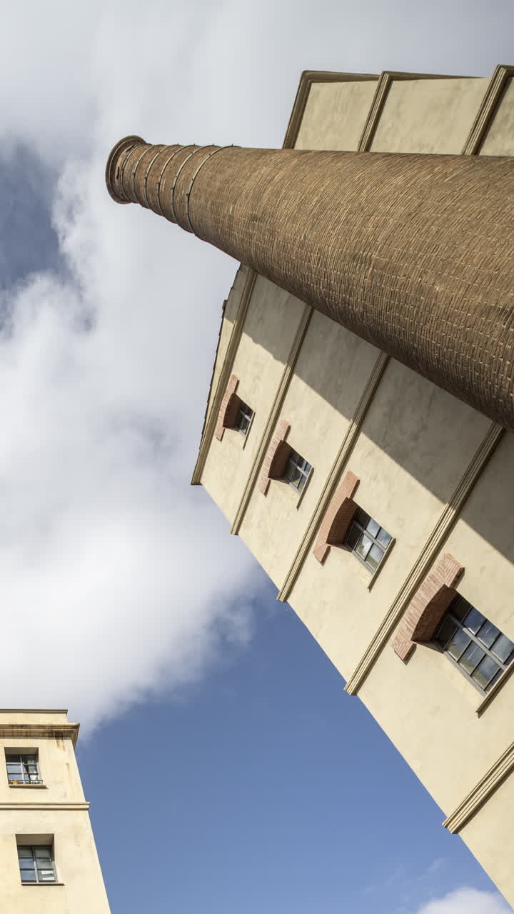 Old factory chimney and apartment buildings in barcelona in vertical