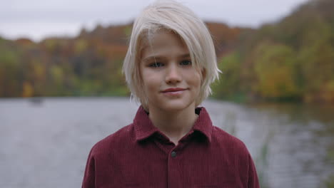 portrait of a young blonde child by a lake in autumn