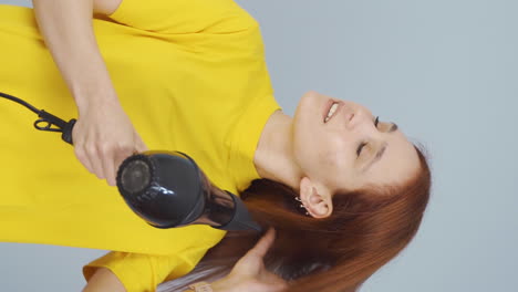 Vertical-video-of-Woman-blow-drying-her-hair.