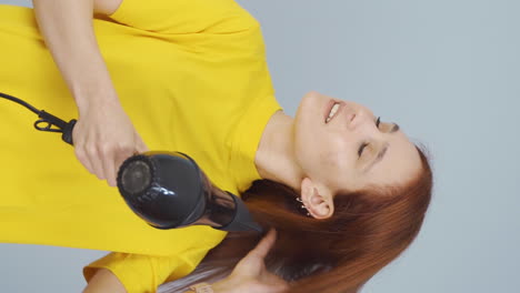 vídeo vertical de una mujer secándose el cabello.