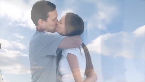 animation of clouds over happy caucasian couple kissing