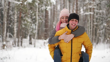 happy loving couple walking in snowy winter forest, spending christmas vacation together. outdoor seasonal activities. lifestyle capture.