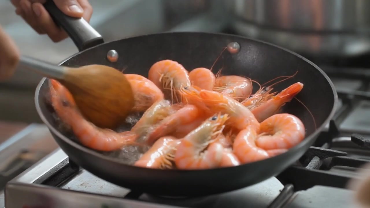 Kok sauterer friske rejer på en stegepande