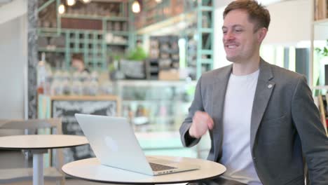 successful young businessman celebrating on laptop in cafe