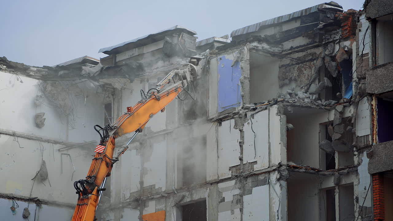 Excavator destroying demolished building. Breaking down old big house.