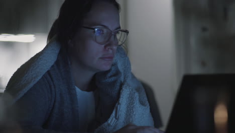 correos electrónicos nocturnos: mujer congelada envuelta en una manta cálida