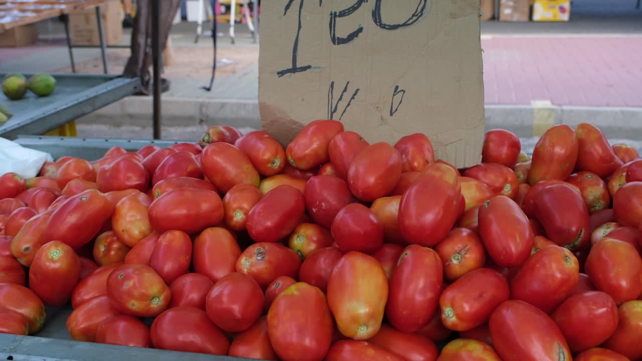 Piles of vibrant, fresh tomatoes in rich red hues are beautifully displayed at the bustling Saturday open-air market, offering a feast for the eyes and tastebuds.