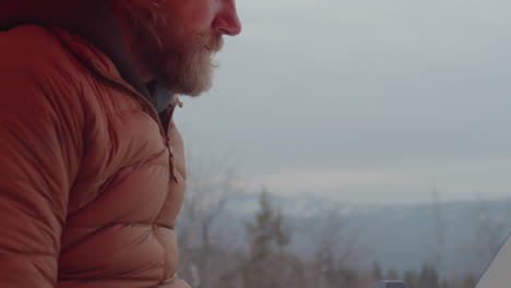 photographer working on laptop in tent at campsite in mountains