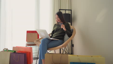 a young woman buying lots of items online with her laptop and credit card