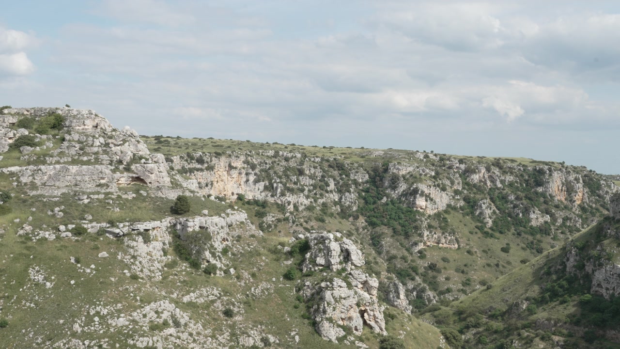 Una splendida vista paesaggistica di un aspro burrone roccioso e ripide scogliere naturali di calcare coperte da vegetazione verde nella Provincia di Matera, Italia