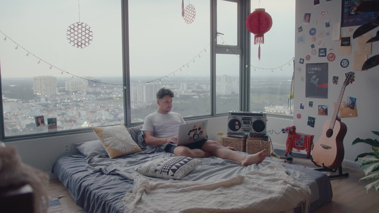 Man Using Laptop in Bedroom at Home