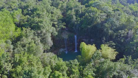 Toma-Aérea-Hacia-Atrás-De-Una-Cascada-Tropical-Rodeada-De-Densos-árboles-De-Bosque-Tropical-En-Verano---Salto-Alto,bayaguana