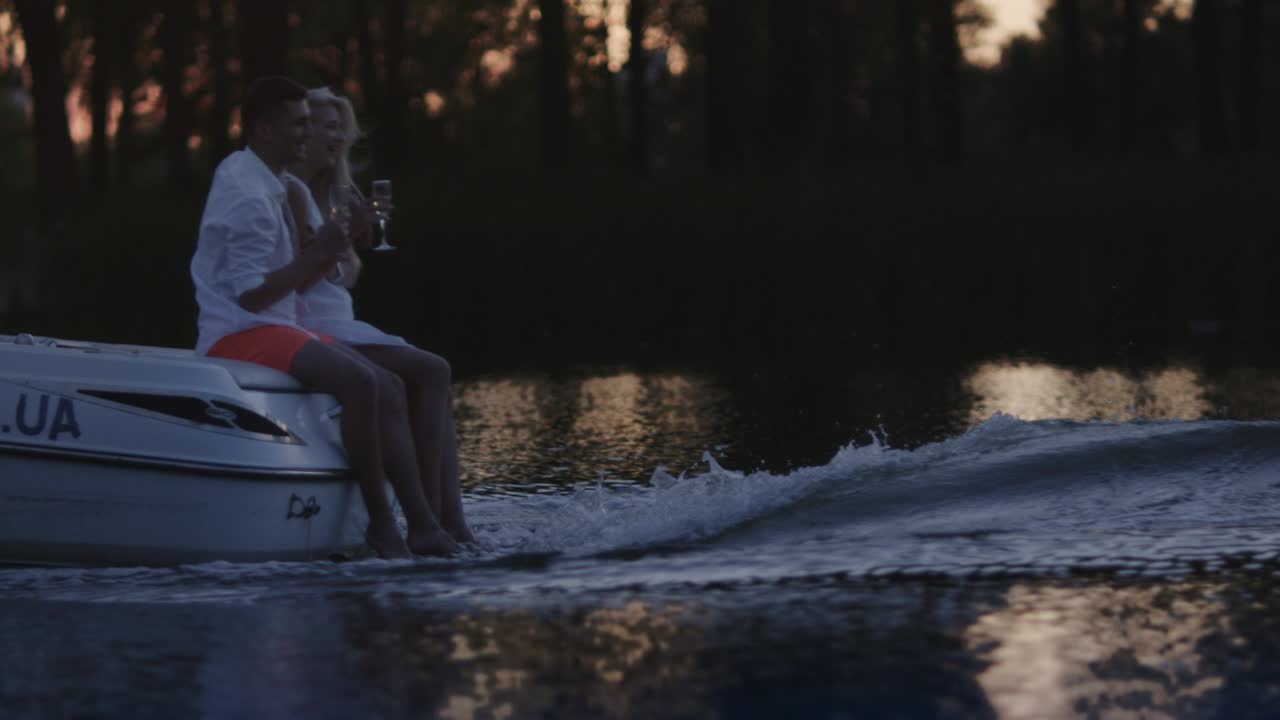 Young people drinking champagne on floating motor boat. Boating on river