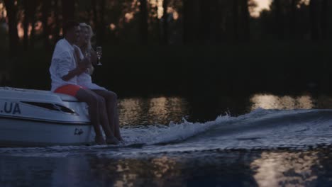 young people drinking champagne on floating motor boat. boating on river