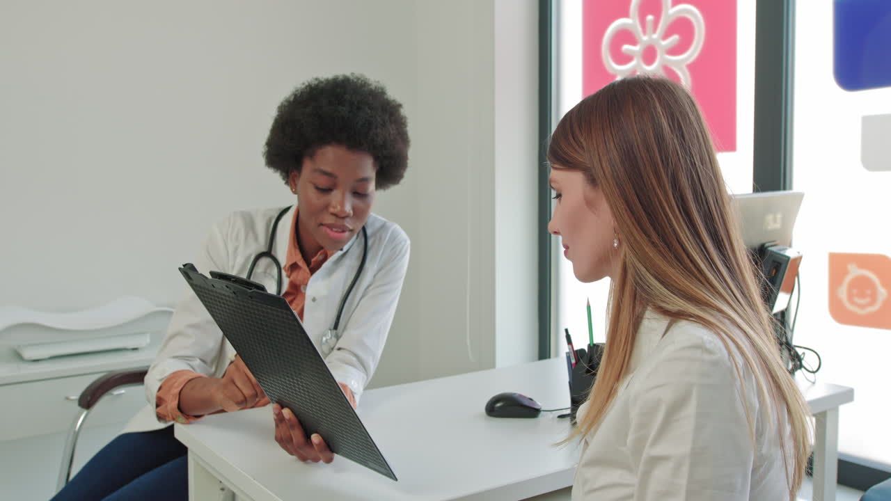 Primer plano del retrato de una joven y guapa doctora afroamericana en su lugar de trabajo hablando con un paciente