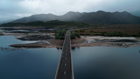 Vista-De-Perfil-Del-Puente-Vacío-El-Fin-De-Semana-Sobre-El-Lago-Burbury-Con-Hermosas-Montañas-Al-Fondo-En-Tasmania,-Australia