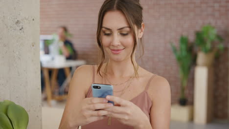 retrato de una hermosa mujer joven usando un teléfono inteligente enviando mensajes de texto navegando en línea feliz leyendo mensajes de redes sociales en el trabajo