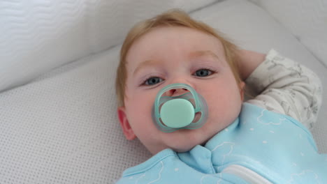 cute caucasian baby boy lying in bed, waking up, close up