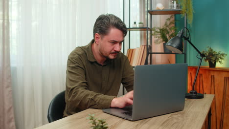 middleaged man frowning laptop frustrated by error bad news virus warning stressful work at table