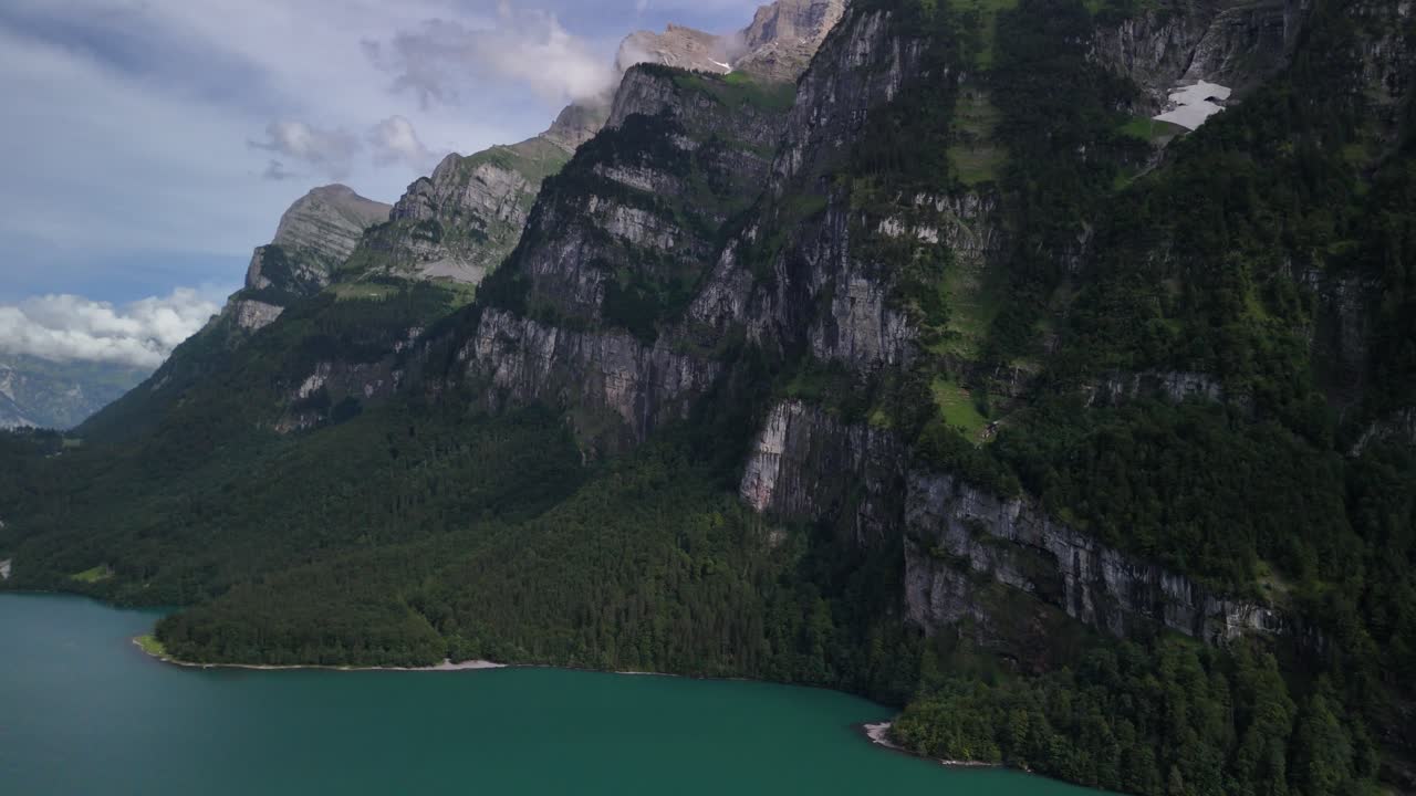 impresionante vista aérea del valle de klöntalersee en suiza, rodeado de majestuosas montañas, que presenta un paisaje sereno y pintoresco ideal para conceptos de belleza natural y retiros pacíficos.