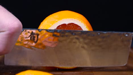 sharp kitchen knife slicing a juicy vibrant blood orange in half