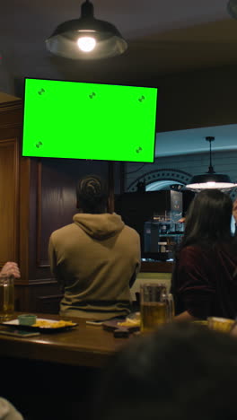 Vertical-shot-of-African-American-fan-celebrating-with-friends-when-football-team-scores-goal-and-wins-the-tournament.-Group-of-multicultural-friends-watch-live-soccer-match-sitting-in-sports-bar-or-pub.